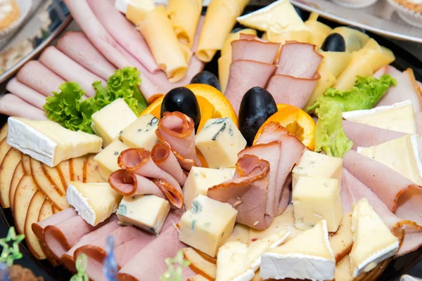 다양 한 종류의 고기와 치즈의 진미가 빛 이 있는 배경 위에 놓인 접시에 배열 된 행사를 위한 음식을 준비하는 일 - 선택적 인 초점 — 스톡 사진