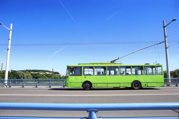 トロリーバス大橋 青いバリアまたはガード レールに対して 道路上の移動緑のトロリーバス — ストック写真