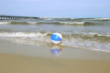 Kum ve deniz sallayarak üzerinde renkli plaj topu. Tatil plaj topu ufuk Baltık Denizi ve Palanga Köprüsü yakınlarında.
