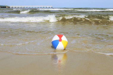 Kum ve deniz sallayarak üzerinde renkli plaj topu. Tatil plaj topu ufuk Baltık Denizi ve Palanga Köprüsü yakınlarında.