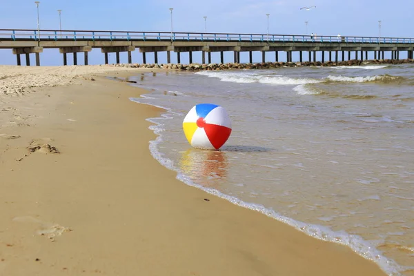 Kum ve deniz sallayarak üzerinde renkli plaj topu. Tatil plaj topu ufuk Baltık Denizi ve Palanga Köprüsü yakınlarında.