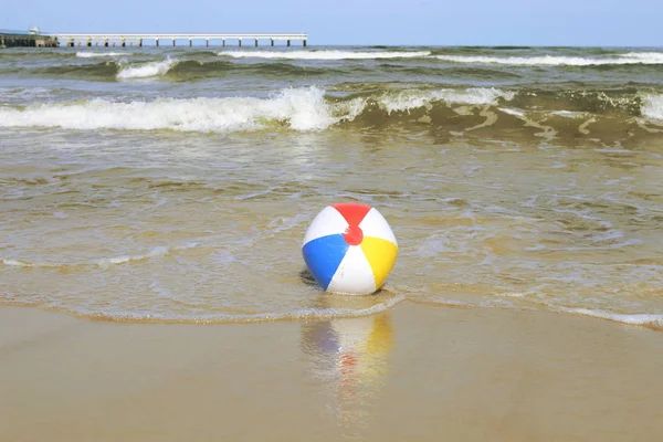 Kum ve deniz sallayarak üzerinde renkli plaj topu. Tatil plaj topu ufuk Baltık Denizi ve Palanga Köprüsü yakınlarında.