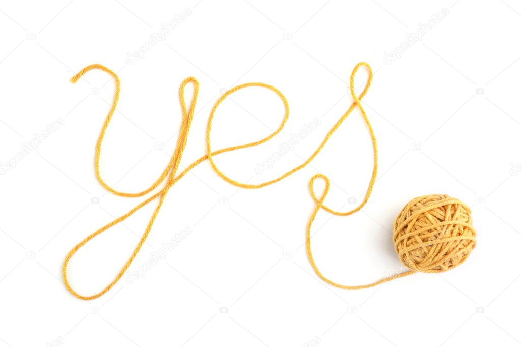Word yes made of yellow thread and thread ball isolated on white background. Cotton thread ball with word yes.