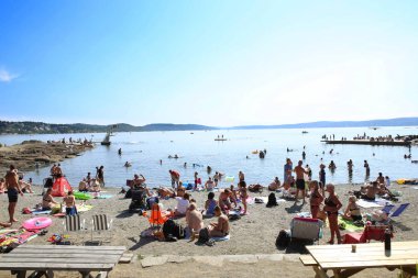 Oslo, Norveç - 22 Temmuz 2018: Oslo Fiyordu Beach'te. Deniz Ulvoya adada iç Oslofjord, sadece şehir merkezinin doğusunda yer almaktadır. Güneşlenme ve yüzme sahilde sıcak yaz gününde insanlar sakin ol.