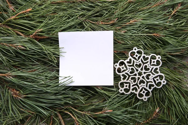 White empty frame and decorative snowflake on green pine branches background. Blank card with winter christmas decoration snowflake on  pine branches.