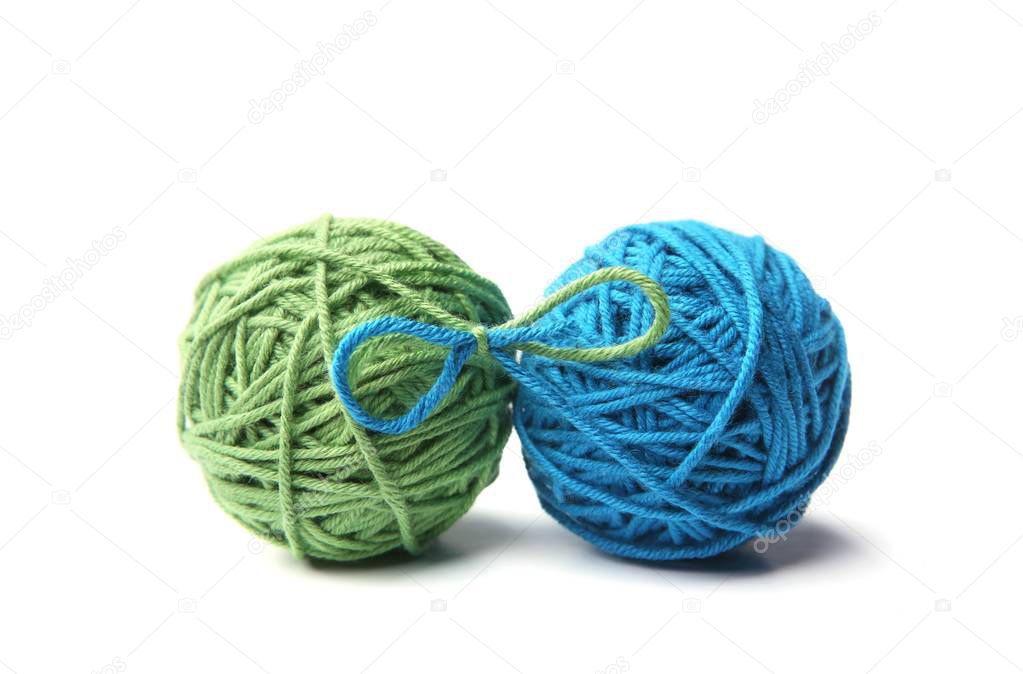 Two green and blue cotton thread balls tied in bow isolated on white background.  Different color green and blue thread balls. 