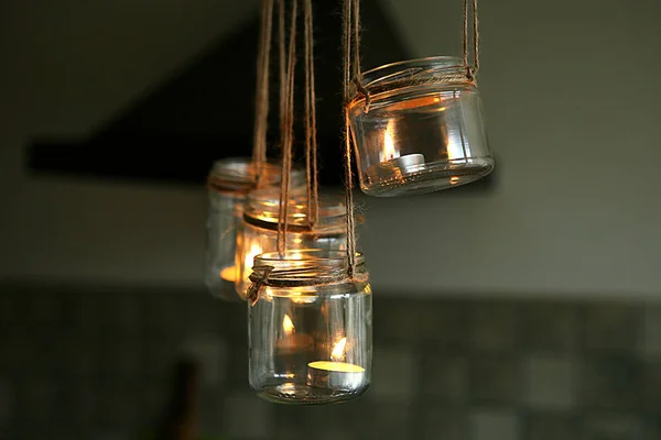 Aromatic candles in glass jars hanging in kitchen. DIY candles in glass jars hanging on linen jute.