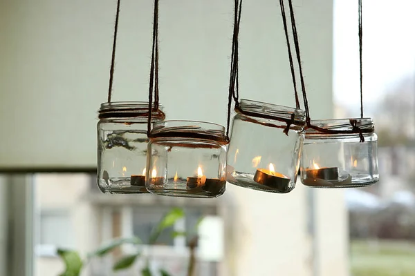 Aromatic candles in glass jars hanging in kitchen. DIY candles in glass jars hanging on linen jute.