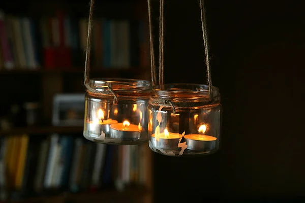 Aromatic candles in jars hanging in interior. DIY candles in glass jars hanging on linen jute.