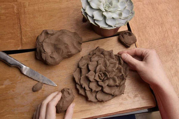 Closeup of hands sculpt clay plant decoration. Hands modeling crafts pottery. Sculpting clay in the process.