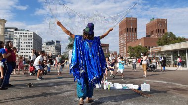 Oslo, Norveç - 11 Temmuz 2019: Arka planda belediye binası ile Aker Brygge ilçesinde Magic kabarcıklar üreticisi. Sokakta Bubbles üreticisi performansı