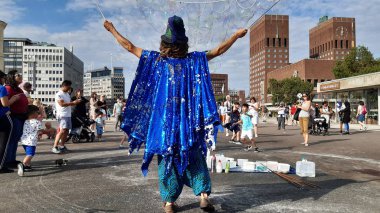 Oslo, Norveç - 11 Temmuz 2019: Arka planda belediye binası ile Aker Brygge ilçesinde Magic kabarcıklar üreticisi. Sokakta Bubbles üreticisi performansı