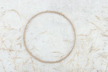 Yuvarlak jüt çerçeve, taş kaplamalı kurumuş çimenler. Kurutulmuş bitki bileşimi ve kapalı alanda daire şeklinde çerçeve.