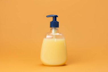 Bej arka planda bir şişe sarı sabun. Temiz eller kavramı. Şampuan, Sıvı Sabun, Aromatik Banyo Tuzu ve Diğer Tuvaletler.