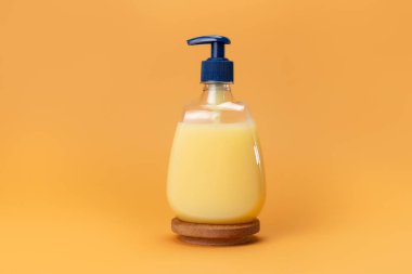 Bej arka planda bir şişe sarı sabun. Temiz eller kavramı. Şampuan, Sıvı Sabun, Aromatik Banyo Tuzu ve Diğer Tuvaletler.