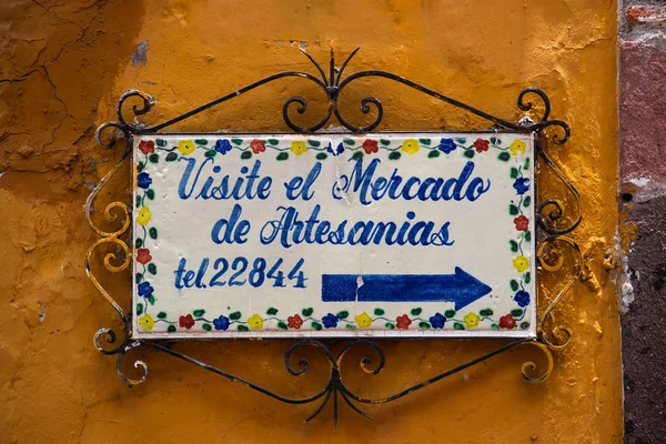 Vintage Street Sign in San Miguel de Allende. Reads: Visit the handcratd market.