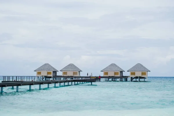 Виллы с водой и деревянный мост на тропическом пляже на Мальдивах — стоковое фото