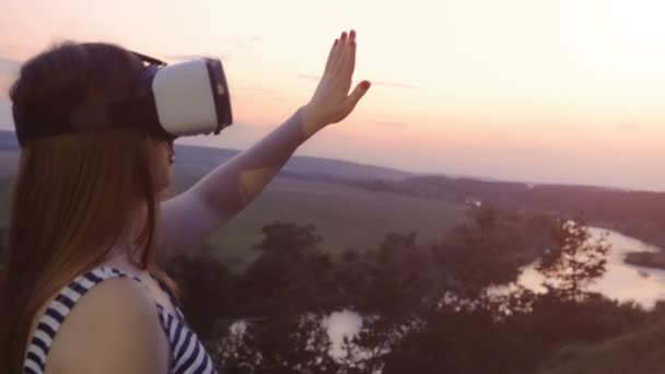 Gyönyörű lány használja a virtuális valóság szemüveg vr lassítva vörös naplemente — Stock videók