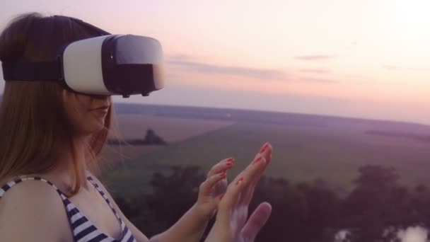 Menina bonita usa óculos de realidade virtual vr no pôr do sol escarlate em câmera lenta — Vídeo de Stock