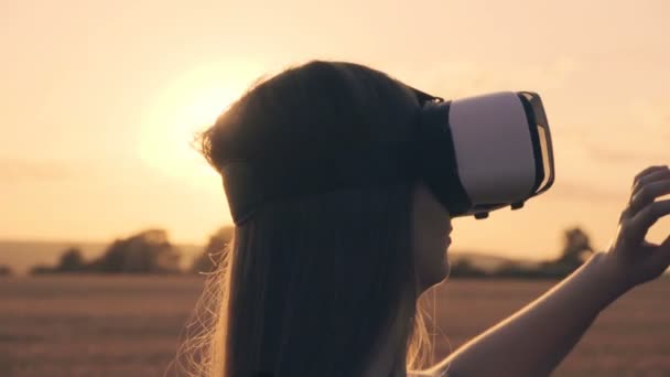 Красивая девушка в золотом поле пшеницы использует очки виртуальной реальности на закате в замедленной съемке — стоковое видео
