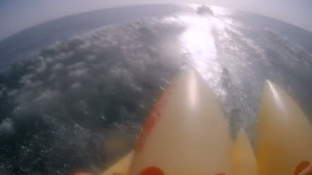 Vue à la première personne de l'équitation sur une grande banane jaune dans la mer, divertissement extrême, éclaboussures volent à la caméra — Video