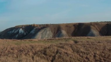 Sinematik dolly zoom etkisi 4k havadan görünümü. Yeşil çimenli kayalık tebeşir tepeler, dağlar ve bir nehir üzerinde uçan