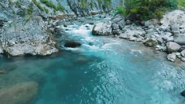 山の川の空中4kトップビュー。高山の川は森の中の岩の峡谷に流れる。夏になると、氷河の雪解けにより川が厚くなる. — ストック動画