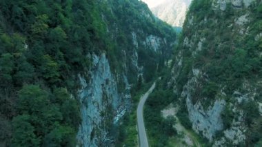 Dağların havadan 4k görünümü. Gün batımında ağaçlar ve bitki örtüsü ile büyümüş güçlü kayalıklar arasında dağların geçitçarpıcı bir geçit