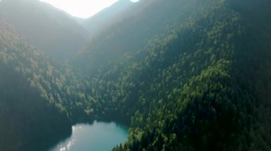 Turkuaz su ve yeşil ağaç ile dağ gölü. Dağlar, orman ve göl ile güzel yaz manzara. Havadan 4k Görünüm. Drone güzel bir dağ ormanı gölü üzerinde vuruldu