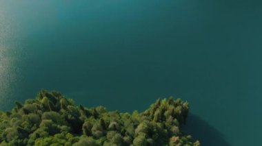 Turkuaz su ve yeşil ağaç ile dağ gölü. Dağlar, orman ve göl ile güzel yaz manzara. Havadan 4k Görünüm. Drone güzel bir dağ ormanı gölü üzerinde vuruldu