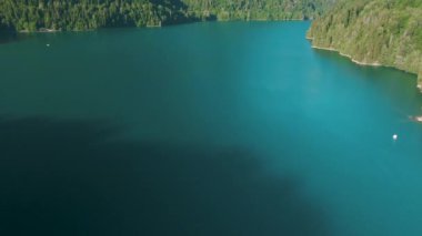 Turkuaz su ve yeşil ağaç ile dağ gölü. Dağlar, orman ve göl ile güzel yaz manzara. Havadan 4k Görünüm. Drone güzel bir dağ ormanı gölü üzerinde vuruldu