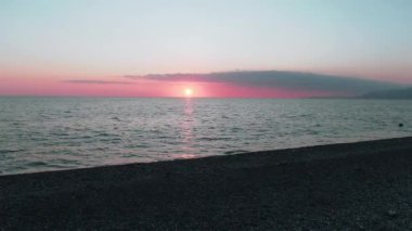 Havadan 4k görünüm. Deniz üzerinde çarpıcı gün batımı güneşi. Güzel sinema sahnesi. Altın güneş ufukta batıyor, su yüzeyinin üzerinde uçuyor.