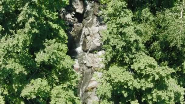 Vista aerea 4k. Un piccolo torrente di montagna, un ghiacciaio che si scioglie formando una cascata nella catena montuosa — Video Stock