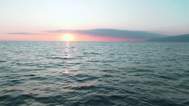 空中4Kビュー。海の上に見事な夕日の太陽。美しい映画シーン。地平線上に金色の太陽が沈み、スローモーションで水面の上を飛ぶ — ストック動画
