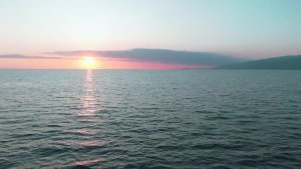 Vista aérea 4k. Um pôr-do-sol deslumbrante sobre o mar. Bela cena cinematográfica. Sol dourado se põe sobre o horizonte, voando acima da superfície da água — Vídeo de Stock
