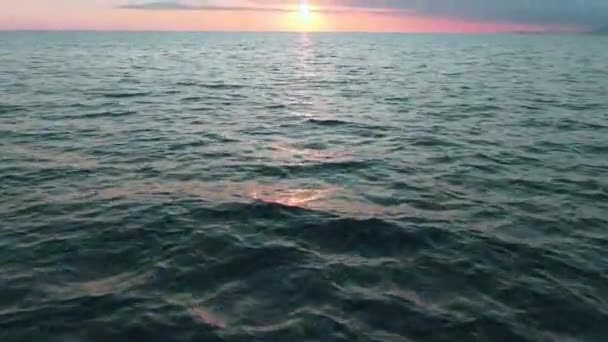Вид снизу. Потрясающее солнце заката над морем. Красивые кинематографические сцены. Золотое солнце заходит за горизонт, летит над поверхностью воды — стоковое видео