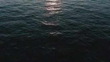 Havadan 4k görünüm. Deniz üzerinde çarpıcı gün batımı güneşi. Güzel sinema sahnesi. Altın güneş ufukta batıyor, su yüzeyinin üzerinde uçuyor.