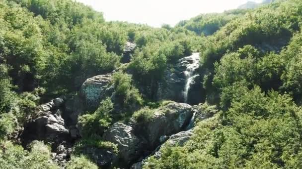 Aerial 4K-vy. En liten fjällbäck, en smältande glaciär som bildar ett vattenfall i bergskedjan — Stockvideo