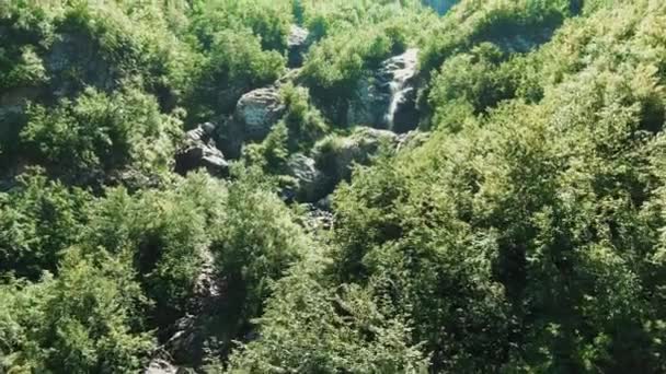 Vista aérea 4k. Um pequeno riacho de montanha, uma geleira derretida formando uma cachoeira na cordilheira — Vídeo de Stock