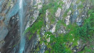 Havadan 4k görünüm. Küçük bir dağ deresi, dağ lık bir şelale oluşturan eriyen bir buzul.