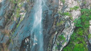 Havadan 4k görünüm. Küçük bir dağ deresi, dağ lık bir şelale oluşturan eriyen bir buzul.