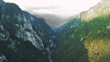 Havadan 4k görünüm. Gün batımında güzel sıradağların üzerinde uçuyor. Güçlü uçurumlar ve geçitler
