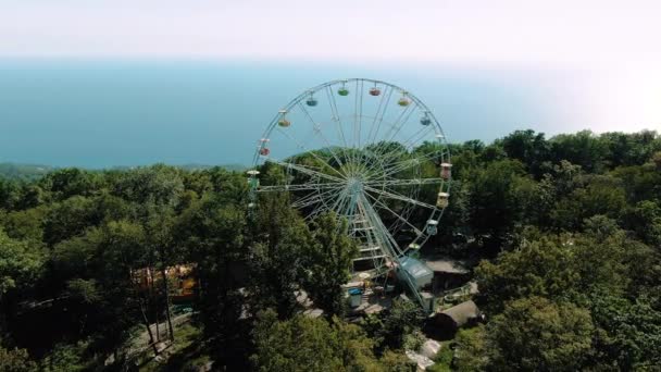 Aerial 4k view. A ferris wheel spins on top of a mountain. Stunning views of the mountains and the sea. Attraction for adults and children — Stock Video