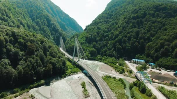 Luchtfoto 4k-weergave. Hangbrug over de rivier. Vliegen over de brug tussen bergen en rotsen. — Stockvideo