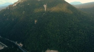 Havadan 4k görünüm. Gün batımında güzel sıradağların üzerinde uçuyor. Güçlü uçurumlar ve geçitler