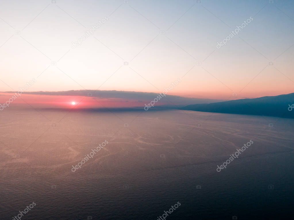Aerial photo from flying drone of a fascinating nature landscape with dramatic evening sunset sky which reflected in sea water with calm waves. Beautiful scenery of a Indian Ocean with sunrise