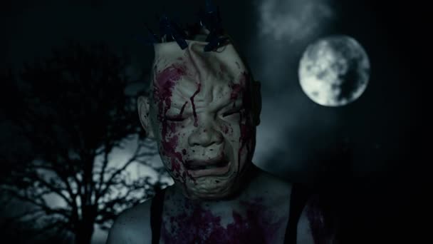 夕暮れ時の満月と枯れ木を背景に、墓地の血まみれのマスクを着けた怖い男。ホラーキャラクターのコンセプト。怖い所だハロウィーンの背景 — ストック動画