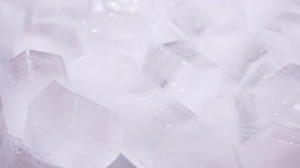 Macro de cubos de hielo de agua clara que se derriten en cámara lenta sobre un fondo blanco. Concepto: agua pura de manantial de montaña, hielo, cócteles, alimentos frescos y congelados . — Vídeo de stock