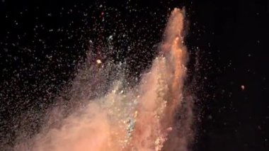 Koyu izole arka planda çok renkli tozun süper yavaş çekim patlaması. Toz yığınları yukarı uçar ve dumanla karışır..