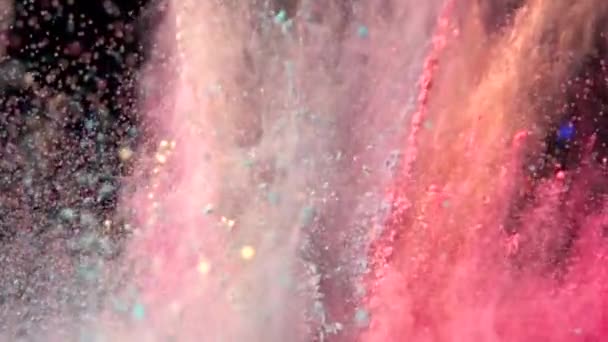 Super slow motion explosion av färgglada flerfärgat pulver på mörk isolerad bakgrund. Pulverklumpar flyger uppåt och blandas med röken. — Stockvideo
